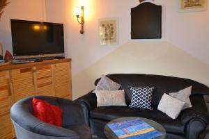 a living room with a black leather couch and a tv at Uroczy domek letniskowy. in Falsztyn