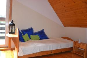 a bedroom with a bed with blue and green pillows at Uroczy domek letniskowy. in Falsztyn +19 photos
