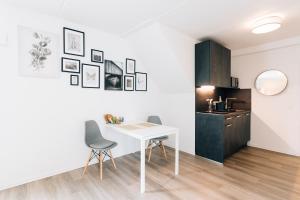 New Living City Appartement في بيليفيلد: طاولة بيضاء وكراسي في غرفة مع مطبخ