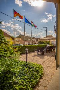 a patio with flags and tables and chairs at Wellness Hotel Kager Harkány in Harkány