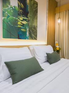 two white beds with green pillows in a bedroom at Cozy Jogja in Kejayan