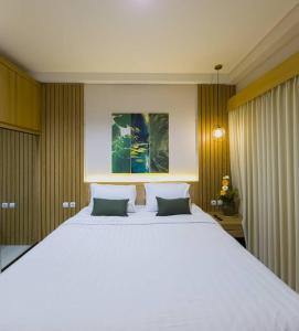 a bedroom with a large white bed with two pillows at Cozy Jogja in Kejayan