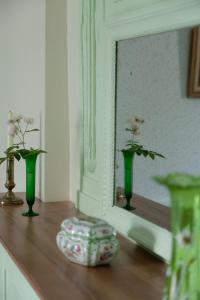 tres jarrones verdes sentados en una mesa frente a un espejo en les chambres fleuries, en Saint-Benoît-du-Sault
