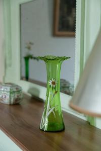 a green vase sitting on top of a wooden table at les chambres fleuries in Saint-Benoît-du-Sault