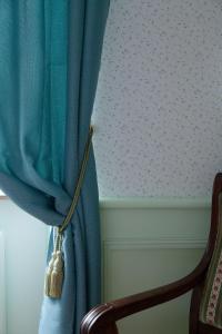 a room with a blue curtain and a chair at les chambres fleuries in Saint-Benoît-du-Sault