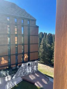 a large glass building with trees in the background at Woodside Apartment in Kopaonik