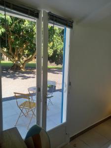 Une porte ouverte s'ouvre sur une terrasse avec une table et des chaises. dans l'établissement La grenadine, à Sainte-Anne-les Hauts