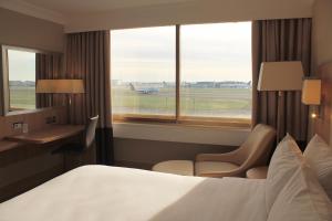 a hotel room with a bed and a desk and a window at Renaissance London Heathrow Hotel in Hillingdon