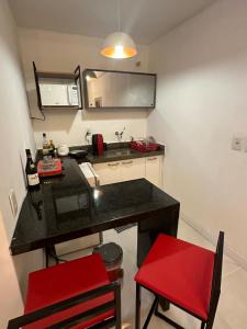 una pequeña cocina con encimera negra y sillas rojas en 952A golden fortaleza en Fortaleza