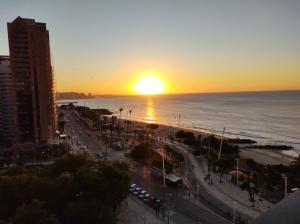 a sunset over a beach with the ocean and a city at 952A golden fortaleza in Fortaleza