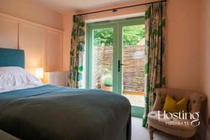 ein Schlafzimmer mit einem Bett, einem Fenster und einem Stuhl in der Unterkunft Foxglove Barn - Rurally located 3 bed equestrian paradise in Aylesbury