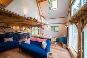 a living room with blue couches and a kitchen at Foxglove Barn - Rurally located 3 bed equestrian paradise in Aylesbury
