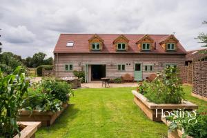 ein großes Haus mit einem Hof mit einigen Pflanzen in der Unterkunft Foxglove Barn - Rurally located 3 bed equestrian paradise in Aylesbury