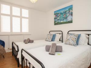 2 Betten in einem Zimmer mit weißen Wänden und Fenstern in der Unterkunft The Cottage in Weymouth