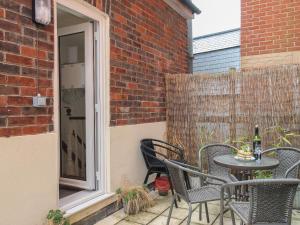 eine Terrasse mit einem Tisch, Stühlen und einem Fenster in der Unterkunft The Cottage in Weymouth