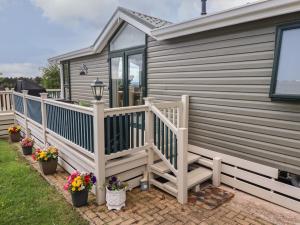 a house with a wooden deck with flowers on it at 15 Silverbirch in Morpeth