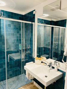 bagno piastrellato blu con lavandino e doccia di Hotel dei Congressi a Castellammare di Stabia