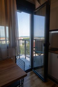een kamer met een tafel en een balkon met glazen schuifdeuren bij Lux Apartman Kovačević in Jagodina