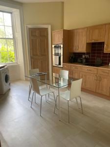 a kitchen with a glass table and white chairs at Private Guest Suite in Georgian Townhouse in City Centre in Edinburgh