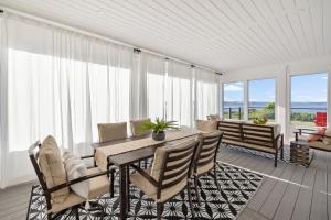 a dining room with a table and chairs and windows at Harbour View Haven in Stratford