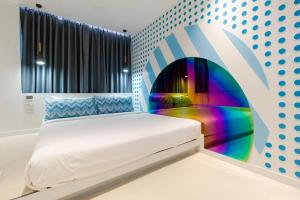 a bed in a room with a colorful wall at Budacco The Living Place in Bangkok