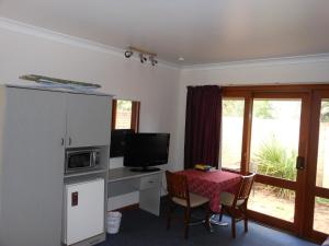a living room with a table with a microwave and a television at Parkway Motel in Queanbeyan
