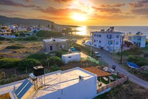 una puesta de sol sobre una ciudad con casas blancas y el océano en Blue Breeze, en Milatos