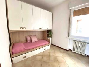 a bedroom with a bed with pink sheets and white cabinets at BELLAVISTA , Bright and Stylish Two Bedroom Apartment in the Historic Center in Ravenna