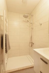 a white bathroom with a shower and a sink at Logement équipé in Saint-Paul-de-Varax