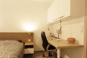 ein Schlafzimmer mit einem Schreibtisch, einem Bett und einem Bett sowie einem Schreibtisch und einem Stuhl in der Unterkunft Logement équipé in Saint-Paul-de-Varax