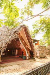 a hut with a thatched roof and a patio at Mangoo Glamping in Melgar