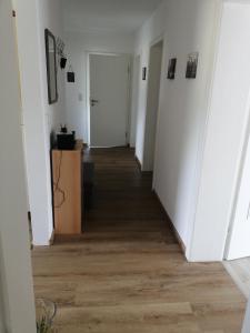 a hallway of an apartment with white walls and wood floors at Ruhige Ferienwohnung am Waldrand. in Wildflecken