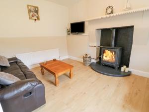 sala de estar con sofá y chimenea en Maghera Caves Cottage en Ardara