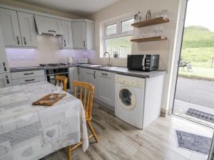 a kitchen with a table and a washing machine at Maghera Caves Cottage in Ardara