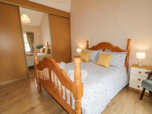 a bedroom with a wooden bed and a mirror at Maghera Caves Cottage in Ardara