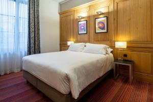 a bedroom with a large bed with a wooden headboard at Hôtel de Bourgtheroulde, Autograph Collection in Rouen