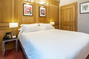 a bedroom with a large white bed and a table at Hôtel de Bourgtheroulde, Autograph Collection in Rouen