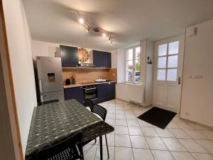 a kitchen with a table and a refrigerator at LE GITE DES 2 FRERES in Arc-en-Barrois