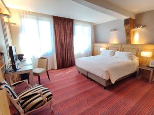 a hotel room with a bed and a desk and a chair at Hôtel de Bourgtheroulde, Autograph Collection in Rouen