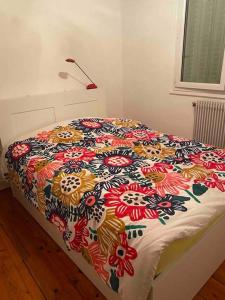 Una cama con una manta de colores encima. en Appartement lumineux Vue montagne Centre Grenoble en Grenoble
