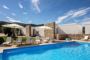 uma piscina com cadeiras e guarda-s�is ao lado de um pr�dio em Cerca Design House no Fund�o