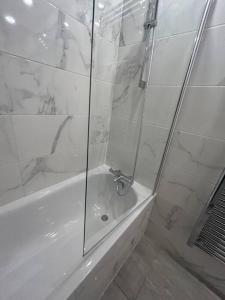 uma casa de banho com um chuveiro e uma banheira com uma porta de vidro em stunning cinematic 2 bed em Hendon