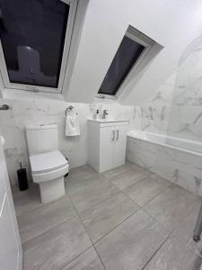 uma casa de banho com um WC, um lavatório e uma banheira em stunning cinematic 2 bed em Hendon