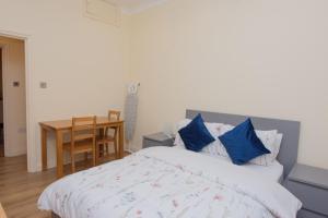 a bedroom with a bed with blue pillows and a table at Evergreen Apartments- Flat 1, London in London