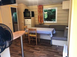 eine kleine Küche und ein Esszimmer mit einem Tisch in einem Wohnwagen in der Unterkunft Camping Parc des Roches-Mobilhome in Saint-Chéron