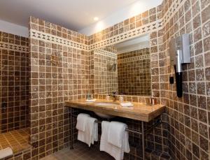 a bathroom with brown tiled walls and a sink at Hôtel de Bourgtheroulde, Autograph Collection in Rouen