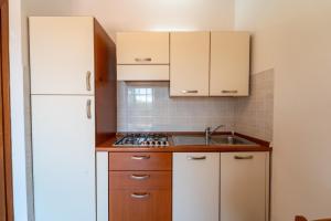 a small kitchen with white cabinets and a sink at Kary Studio Apartment in Olbia