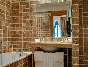 a bathroom with a sink and a tub and a mirror at Hôtel de Bourgtheroulde, Autograph Collection in Rouen +59 photos
