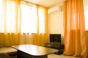 een woonkamer met oranje gordijnen, een tafel en een tv bij Private Rooms Kranevo in Kranevo