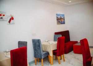 a dining room with a table and red chairs at Dominance Events and Suites in Ibadan